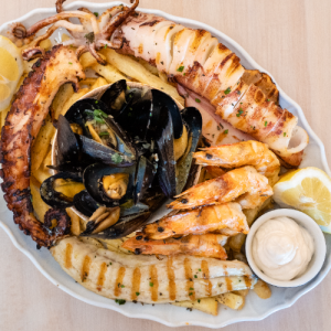Seafood platter for 2 people with grilled shrimps, grilled calamari, griled octopus, steamed mussels, fish fillet, fresh French fries and white fish tarama dip