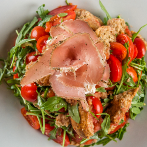 Mykonian with rocket, cherry tomatoes, freshly grated tomato, rusk,“kopanisti” cheese and Mykonian “louza” cold cuts, with extra virgin olive oil